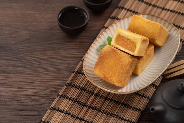 차와 함께 나무 테이블 배경에 접시에 맛있는 파인애플 케이크 페이스트리