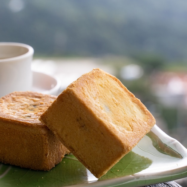 Photo delicious pineapple pastry in a plate for afternoon tea on wooden railing of a teahouse in taiwan with beautiful landscape in background, close up.