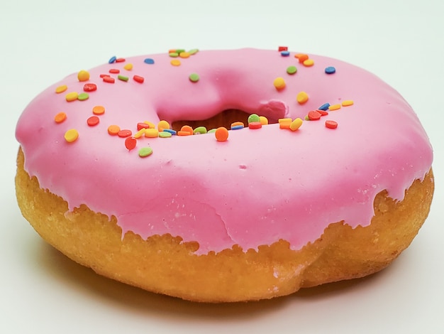 Delicious pink donut on a white wall close-up