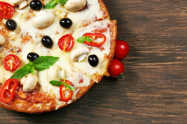Delicious pizza and fresh vegetables on wooden background close up