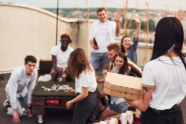 Delicious pizza Group of young people in casual clothes have a party at rooftop together at daytime