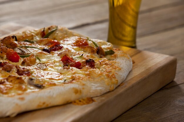 Вкусная пицца подается на деревянной доске с бокалом пива