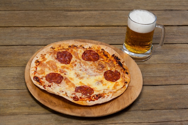 Deliziosa pizza servita sul vassoio della pizza con un bicchiere di birra