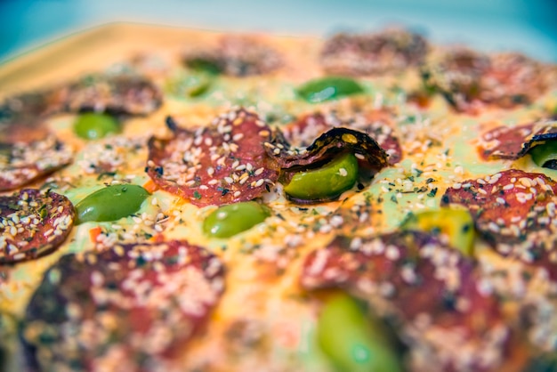 Delicious pizza served on wooden table.  hot tasty delicious rustic homemade american pizza with tomato gherkin salami olives