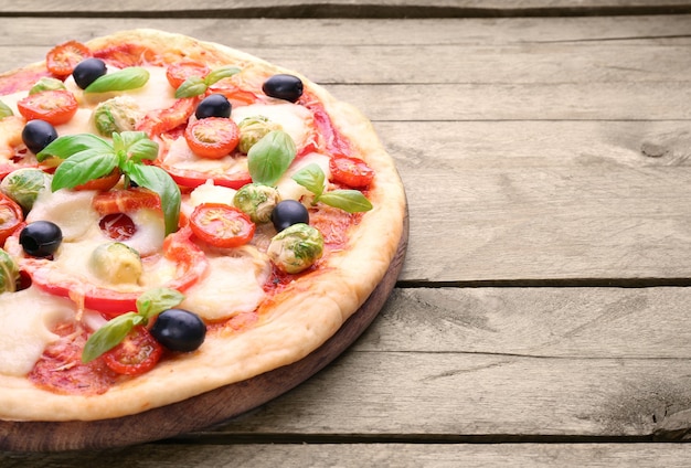 Delicious pizza with cheese and vegetables on wooden table