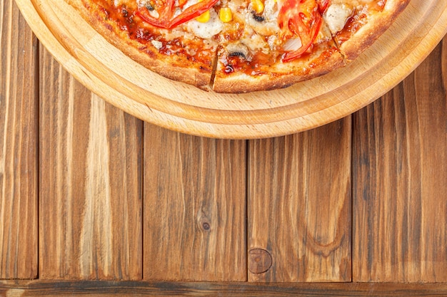 delicious pizza with chicken mushrooms cheese tomatoes and corn on a wooden background closeup