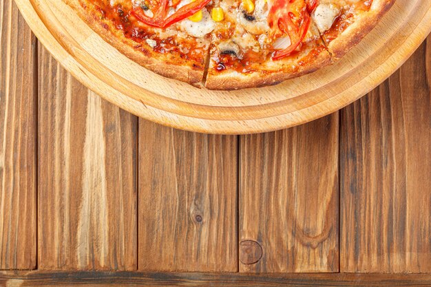Photo delicious pizza with chicken mushrooms cheese tomatoes and corn on a wooden background