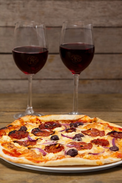 Delicious pizza with glasses of red wine