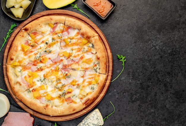 delicious pizza with ham cheese pineapple mango on a stone background with copy space for your te