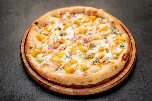 delicious pizza with ham cheese pineapple mango on a stone background