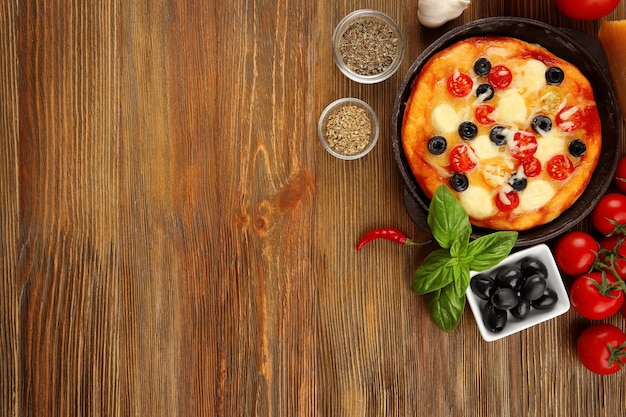 Delicious pizza with ingredients and spices on table