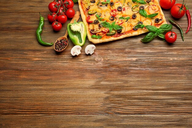 Foto deliziosa pizza con ingredienti su sfondo di legno