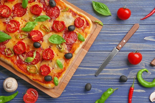 Delicious pizza with ingredients on wooden background