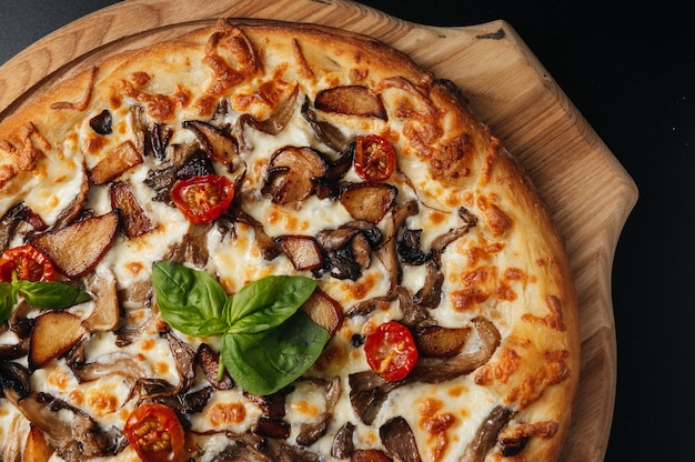 Deliziosa pizza con funghi sulla scrivania in legno su sfondo nero