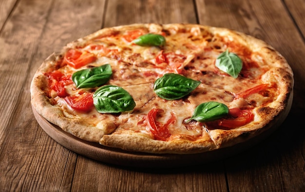 Delicious pizza with tomatoes and fresh basil on wooden background