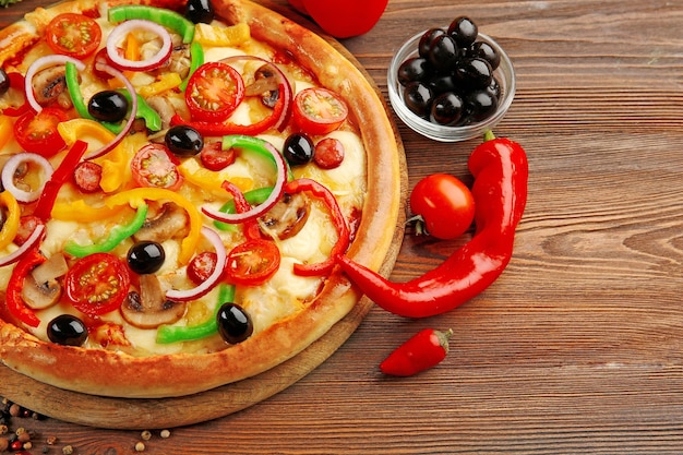 Delicious pizza with vegetables on wooden table