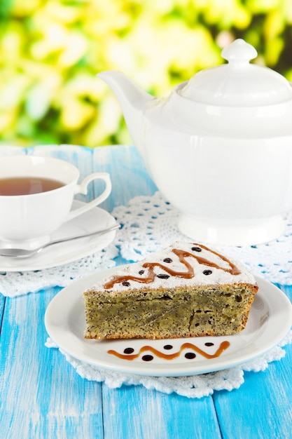 Delicious poppy seed cake with cup of tea on table on bright background