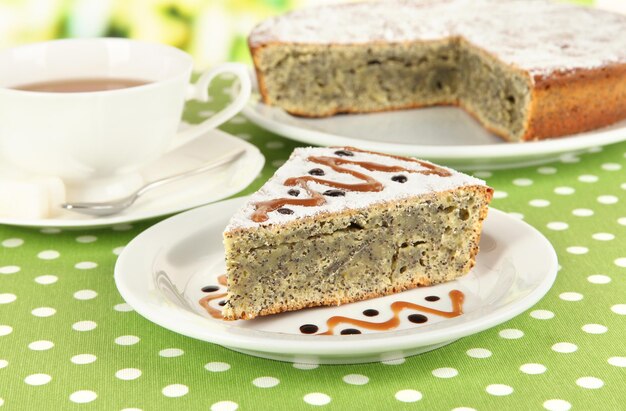 Delicious poppy seed cake with cup of tea on table closeup