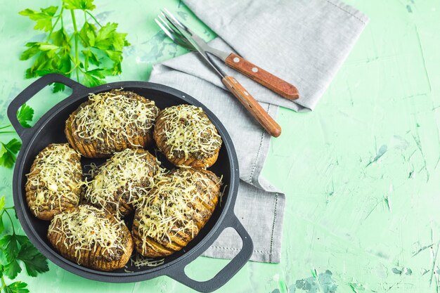 写真 黒いフライパンでジャガイモを焼いたおいしい部分、ペストソースネギとチーズを添えた夕食の料理