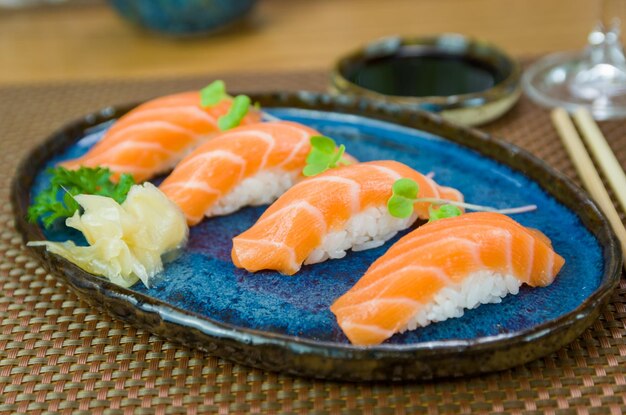 Delicious premium salmon nigiri on blue handmade plate decorated