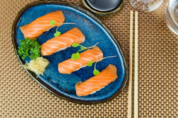 Delicious premium salmon nigiri on blue handmade plate decorated