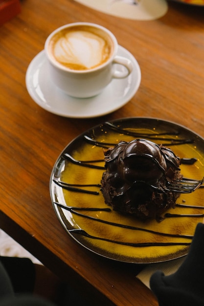 Delicious profiteroles with chocolate on the table