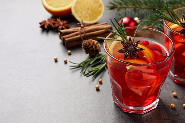 Delicious punch drink with cranberries orange and spices on grey table Space for text