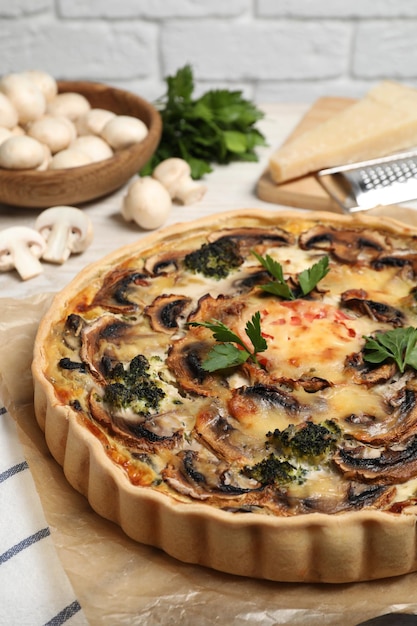 Delicious quiche with mushrooms and parsley on table closeup