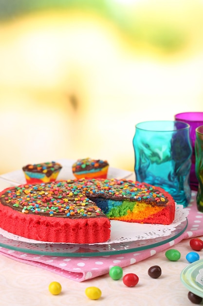 Delicious rainbow cake on table on bright background