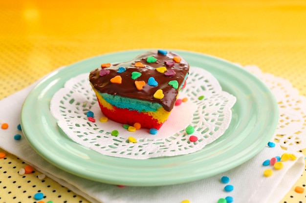 Delicious rainbow mini cake on colorful plate on bright background