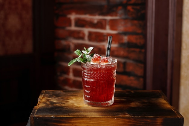 Delicious raspberry alcoholic cocktail with mint on a wooden board near a brick wall