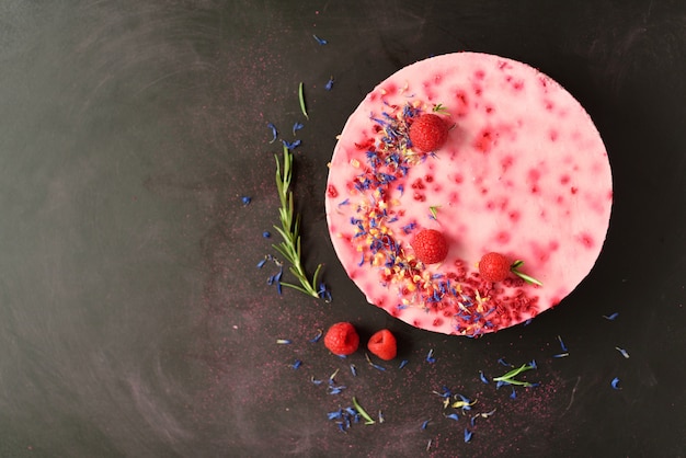 Deliziosa torta di lamponi con bacche fresche, rosmarino e fiori secchi. vegetariano, concetto di cibo vegano