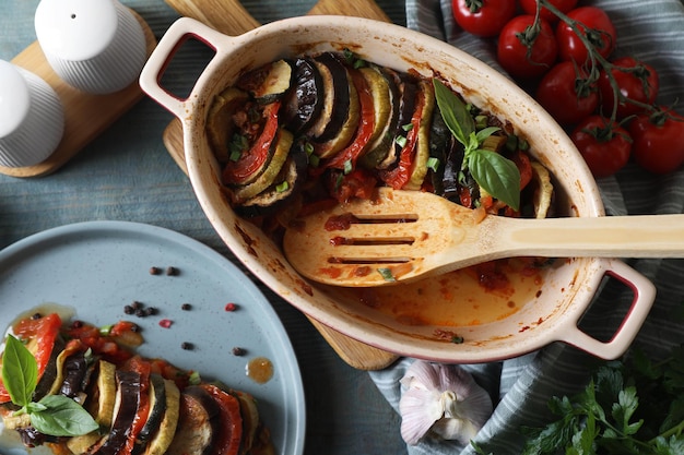 Delicious ratatouille served with basil on grey wooden table flat lay