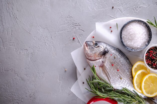 Delicious raw dorado or sea bream fish with lemon spices, fresh rosemary on marble board view from above