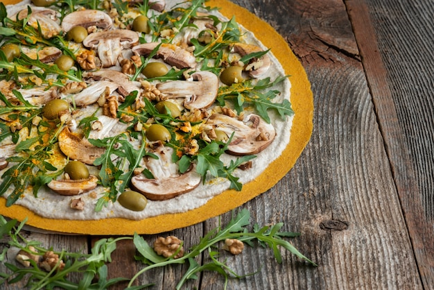 Delicious raw pizza with mushrooms, walnuts, arugula and green olives.