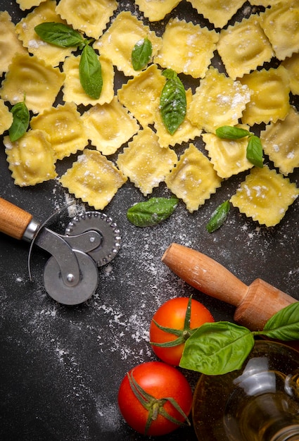 Delicious raw ravioli with flour and basil on dark background. The process of making Italian ravioli.