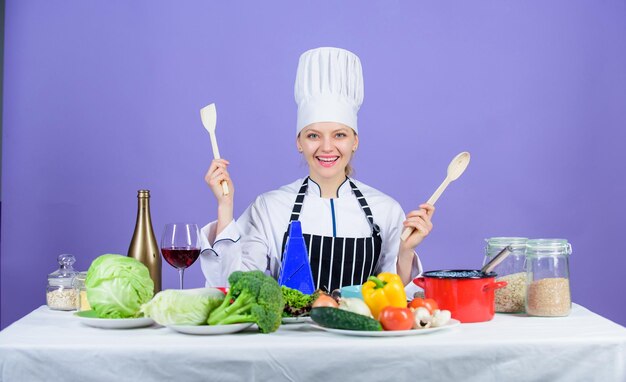 Delicious recipe concept. Gourmet main dish recipes. Cooking is her hobby. Cooking healthy food. Girl in hat and apron. Woman chef cooking healthy food. Fresh vegetables ingredients for cooking meal.