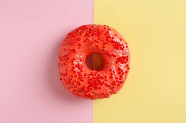 Photo delicious red donut on color background top view