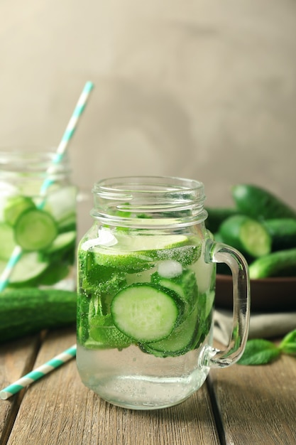 Delicious refreshing water with mint and cucumber in mason jar on wooden table