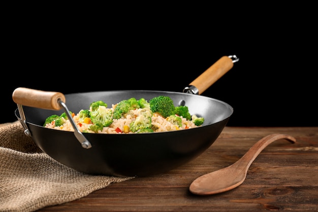 Delizioso pilaf di riso con broccoli nel wok su tavola di legno