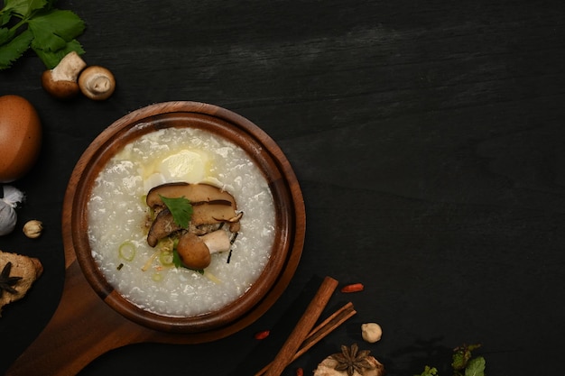 Delicious rice porridge with soft boiled egg shiitake mushroom slice ginger and scallion in wooden bowl Top view with copy space