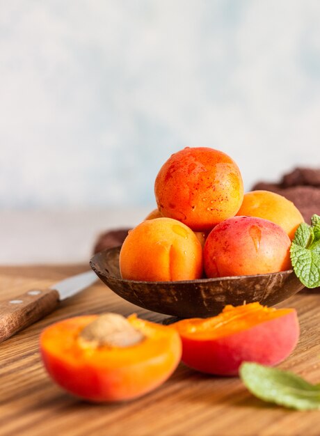 Delicious ripe apricots in a wooden bowl on a wooden cutting board. 