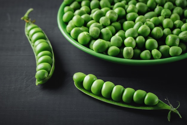 Delicious ripe green peas lying on a wooden table.