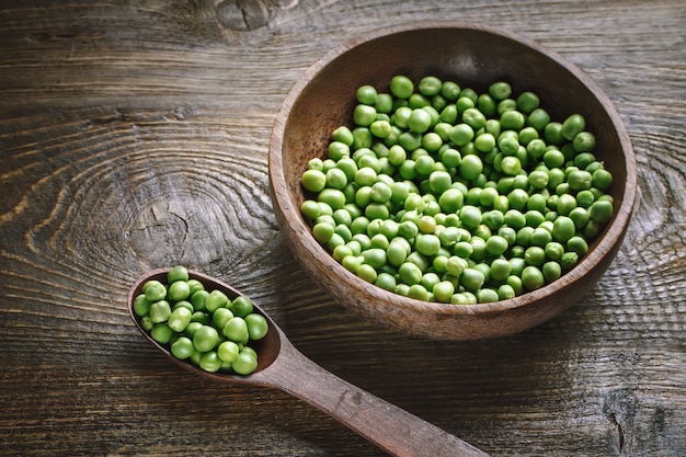 Delicious ripe green peas lying on a wooden table.