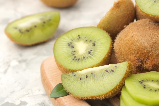 Foto deliziosi lotti maturi di kiwi e kiwi tagliati su una tavola su uno sfondo di cemento chiaro primo piano