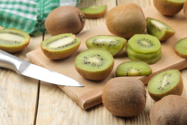 Foto deliziosi lotti maturi di kiwi e kiwi tagliato su un tavolo di legno naturale