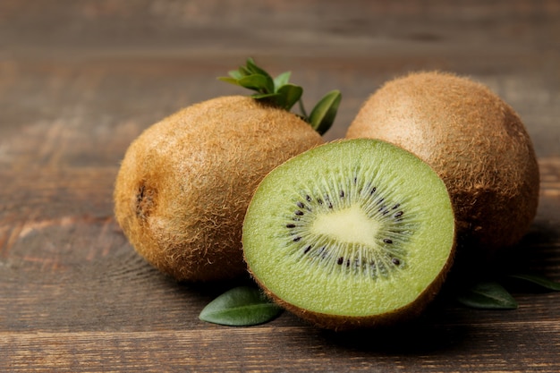 Delicious ripe many kiwi fruit and kiwi in a cut on a brown wooden table. close-up.