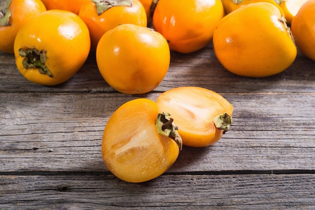 Delicious ripe persimmon fruit on wooden background