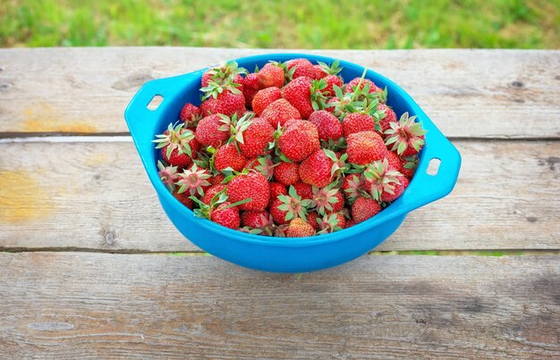 Fragole mature deliziose sulla ciotola, sulla tavola di legno.