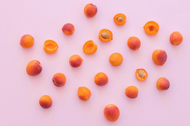 Delicious ripe sweet apricots on pink background flat lay